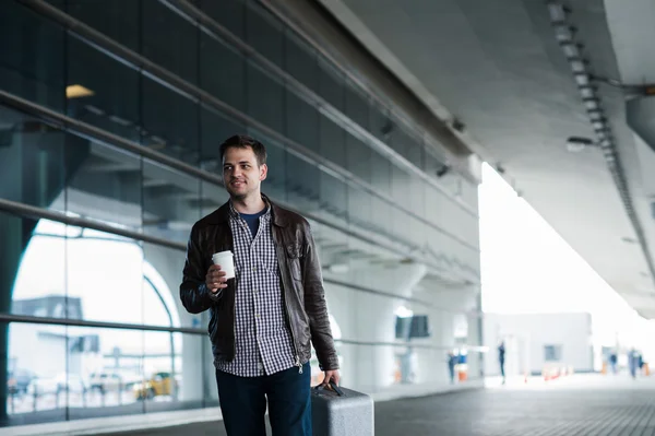 Man in airport holding a bag and walking with cup of coffee — Stock Photo, Image