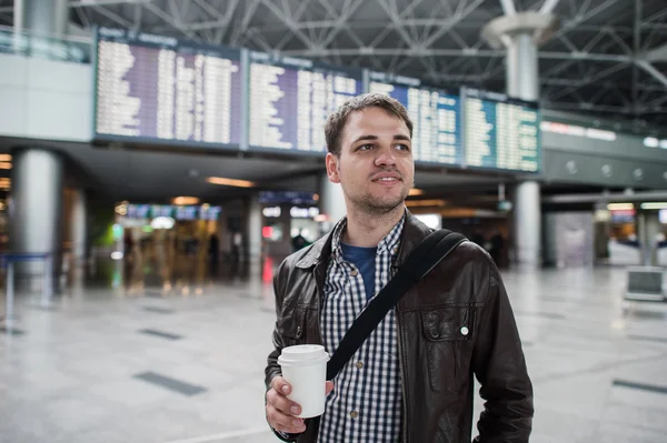 Jonge reiziger man met koffiekopje op de luchthaven over boord vertrekken en aankomsten — Stockfoto