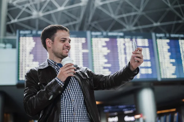 Leende ung resande man på flygplatsen gör selfie framför tidsplan styrelse — Stockfoto