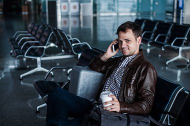 çalışma, bir sandalye şeyler havaalanında uçağı için bekleyen oturan siyah saçlı yakışıklı genç