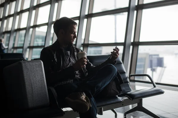 Man te wachten op de luchthaven lounge texting met zijn slimme telefoon — Stockfoto