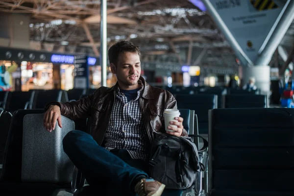 Ung attraktiv man på flygplatsen med hans väska resväska och kaffe — Stockfoto