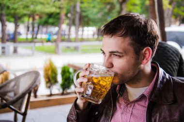 Adam bira içiyor. Yan görünüm yakışıklı genç adam içme lager bira barda otururken sayaç