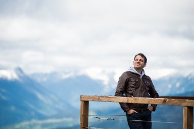 Adam bakış dağlarda. Mutlu ve gülümseyerek, gökyüzüne bakarak.