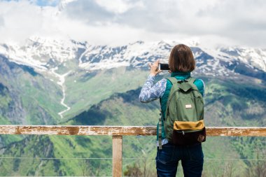 Dağın tepesinde ve güzel arka plan üzerinde akıllı telefon ile alarak resim üzerinde genç ve güzel kadın kız kalmak. Kadın turist Gezgin renkli fotoğraf.