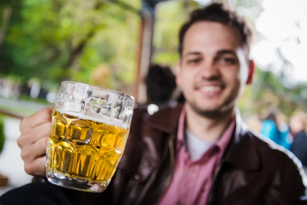 Vértes portréja, jóképű srác iszik az ital, a külső café veranda. Szelektív összpontosít a sör. — Stock Fotó