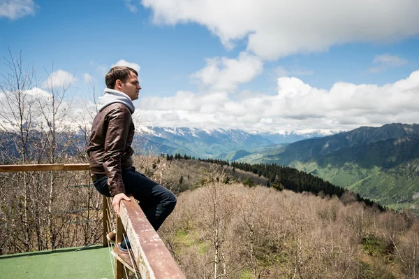 Ung man tittar på utsikten från toppen av berget. — Stockfoto