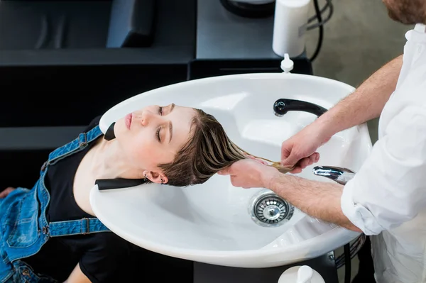 Hair care in modern spa salon. Male hairdresser washing teen girls hairs — Stock Photo, Image
