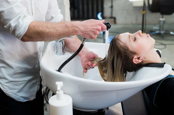 Young teenager girl in hairdressing salon washing hair by male hairdressers hands. — Stock Photo, Image
