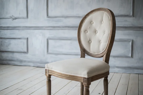 Белый винтажный стул, стоящий перед светлой стеной с лепниной на деревянном паркетном полу . — стоковое фото