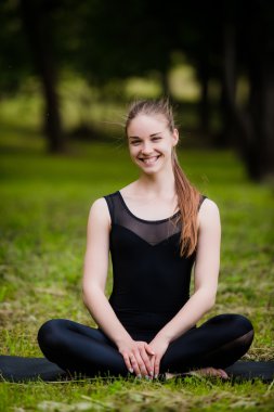 Siyah mat çalışma dışarı, yukarı germe egzersizleri riverbank Park, Vamadevasana varyasyon, tam uzunlukta oturan üzerinde ısınma yapıyor güzel sportif sakin genç kadın