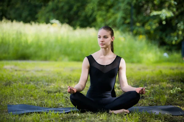 Ung flicka gör yoga i parken — Stockfoto