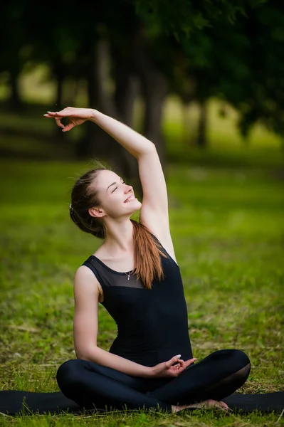 Mulher bonita fazendo exercício de alongamento na grama verde no parque. Treino de ioga — Fotografia de Stock