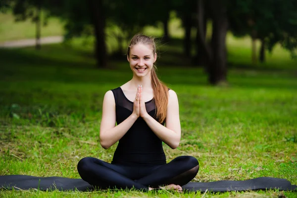 Yoga utomhus i varma hösten solig park. Kvinna sitter i lotusställning zen gestikulerande. Begreppet hälsosam livsstil och avkoppling — Stockfoto