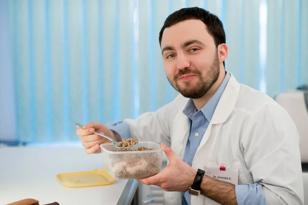 El doctor almorzando en su oficina durante el descanso. Empleado comiendo trigo sarraceno de lonchera contenedor de plástico — Foto de Stock