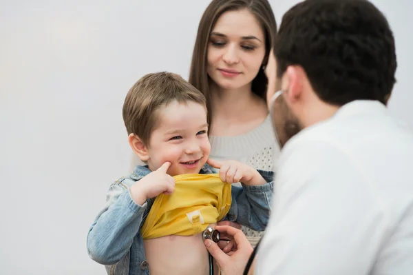 Doctor examinando a un chico de escuela con su madre en la oficina del hospital — Foto de Stock