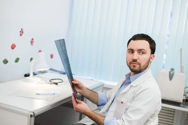 Больничный врач держит пациентов рентгеновской пленкой и МРТ, смотрит в сторону — стоковое фото