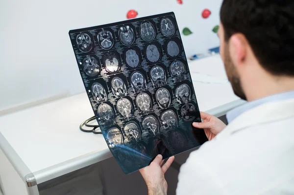 Jovem médico lendo e revisando uma ressonância magnética — Fotografia de Stock