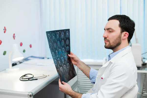 Portret van een knappe Kaukasische mannelijke radioloog x-ray zittend op zijn kantoor te houden — Stockfoto