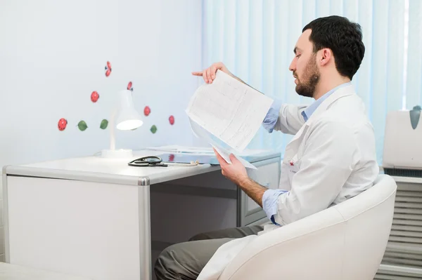 Doctor trabajando con los resultados de las pruebas de su paciente en el consultorio — Foto de Stock