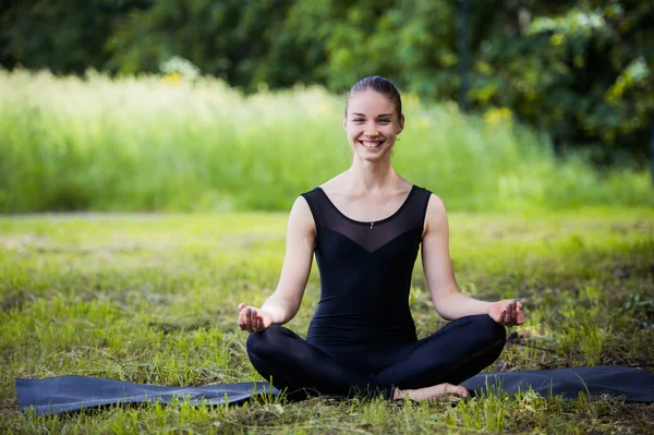 Yoga woman on green grass in lotus pose smiling — Stock Photo, Image