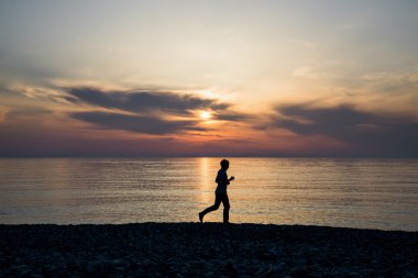 Siluet spor etkin adam çalıştıran ve gün batımında sahilde egzersiz