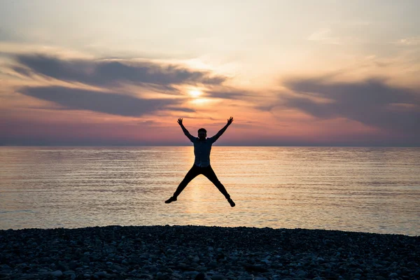 Silhouette of jumping man on sunrise background — Stock Photo, Image