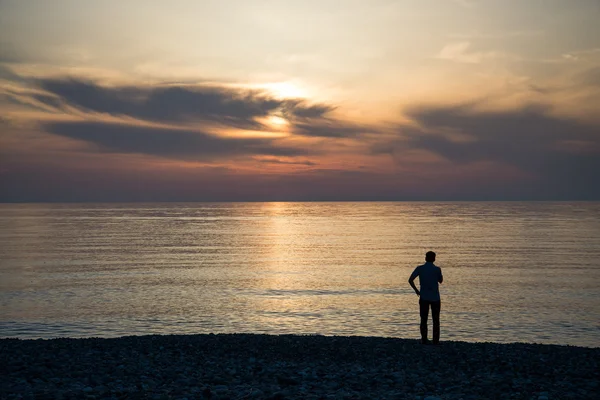 Молодой человек смотрит на восход солнца. — стоковое фото