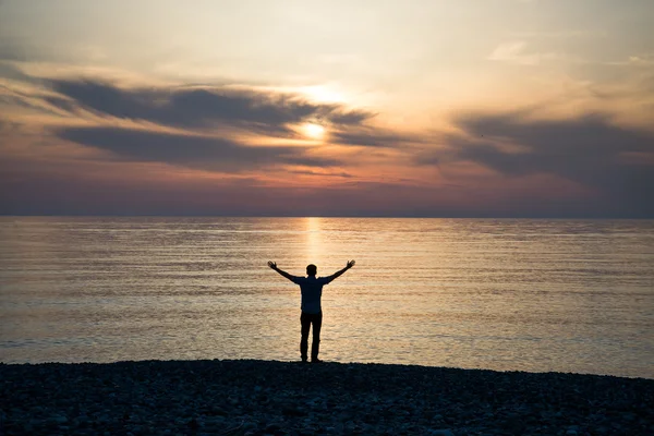 Jeune homme au coucher du soleil lève les mains — Photo