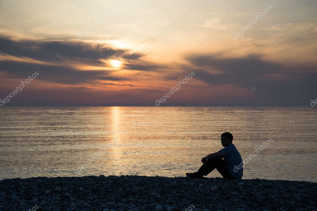 Silhueta de uma sessão de homem com tão triste por do sol.