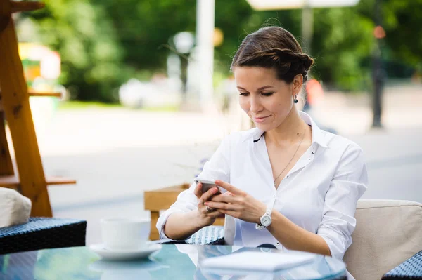 Πορτρέτο μιας γοητευτικής γυναίκας των επιχειρήσεων κουβεντιάζοντας στο έξυπνο τηλέφωνό της, ενώ περιμένει κάποιον στο καφέ σε εξωτερικούς χώρους, πανέμορφο θηλυκό χρησιμοποιώντας το κινητό τηλέφωνο, ενώ κάθεται στο άνετο εστιατόριο στον καθαρό αέρα κατά τη διάρκεια — Φωτογραφία Αρχείου