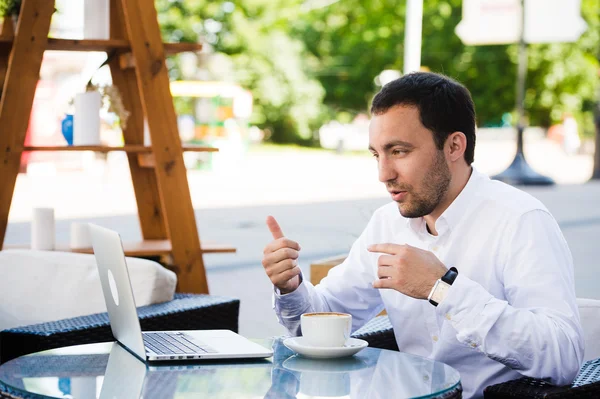 Close-up shot van jonge man glimlachend en het gebruik van digitale Tablet in café. Guy is het doen van ontbijt en het maken van video-oproep met laptop. — Stockfoto