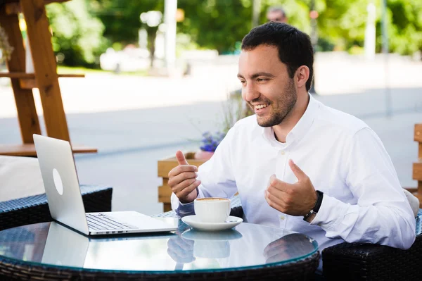 Работай и расслабься. Онлайн-конференция. Бизнесмен, одетый в рубашку, работает с ноутбуком, разговаривает по скайпу в парке кафе на открытом воздухе — стоковое фото