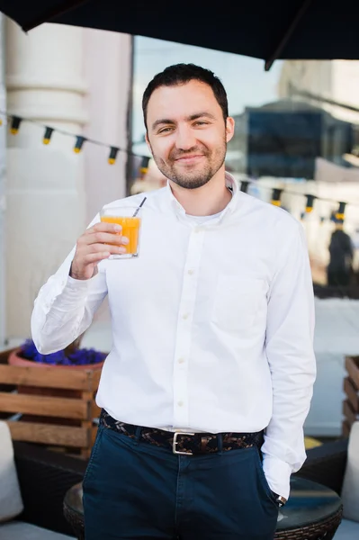 Красивий бізнесмен п'є свіжий апельсиновий сік у відкритому кафе і посміхається камері. Концепція здорового обіду . — стокове фото
