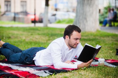 yakışıklı genç işadamı parkta yalan kitap okuma