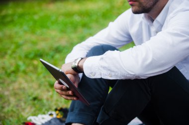 İşadamı kullanarak Tablet bilgisayar Park. Yakın çekim vurdu.