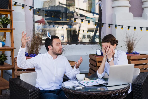 Forretningsmænd chokeret over kollega skrigende og smide papirer i luften på udendørs cafe under frokostpause - Stock-foto