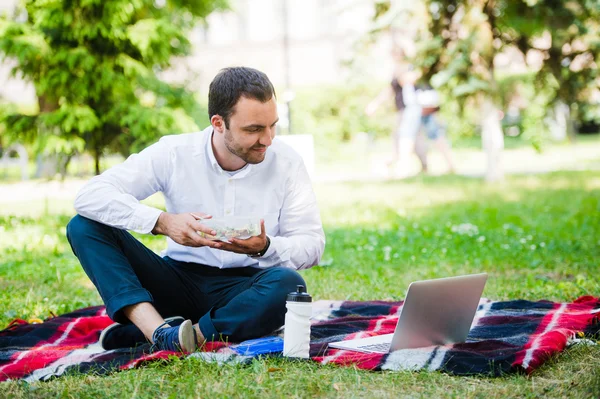 Hombre joven y atractivo se relaja en el parque a la hora del almuerzo — Foto de Stock