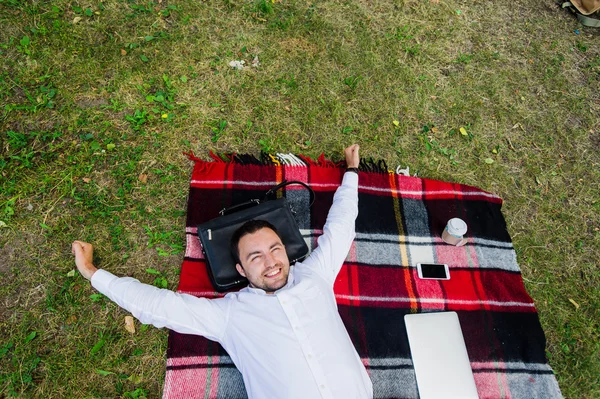 Imago van ontspannen op het gras met laptop in de buurt van door zakenman — Stockfoto