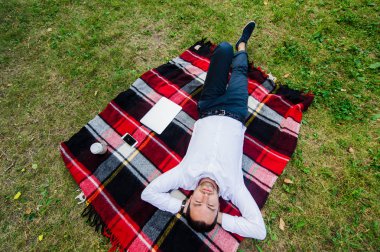 Mutlu genç adam ile laptop çimenlerin üzerinde rahatlatıcı en baştan görüntülemek