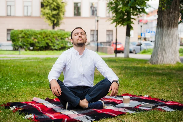 Hombre hombre de negocios meditando al aire libre en pose de loto — Foto de Stock