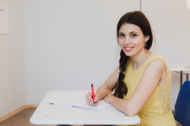 Kadın genç öğrenci eğitim kameraya bakarak ve gülümseyen derste