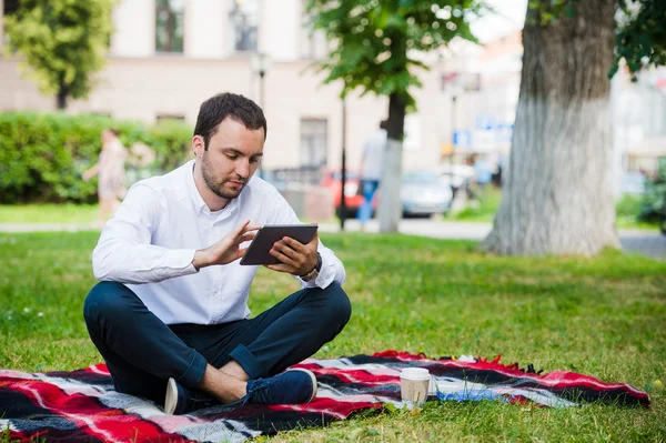 Joven hombre de negocios en el parque trabajando con la tableta —  Fotos de Stock