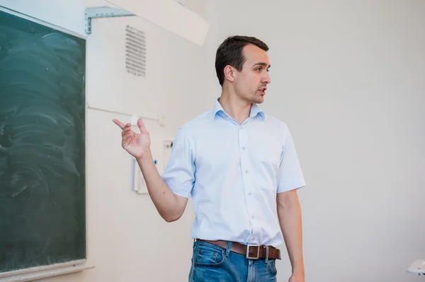 Jeune enseignant près de tableau dans la classe scolaire parler à la classe — Photo