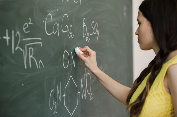 Cukup muda perempuan mahasiswa menulis di papan tulis papan tulis selama kelas kimia — Stok Foto