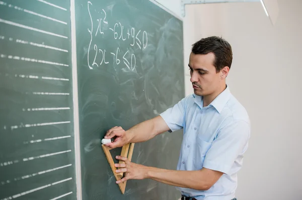 Genç öğretmen veya öğrenci formülü ile bir kara tahta üzerinde üçgen çizmek — Stok fotoğraf