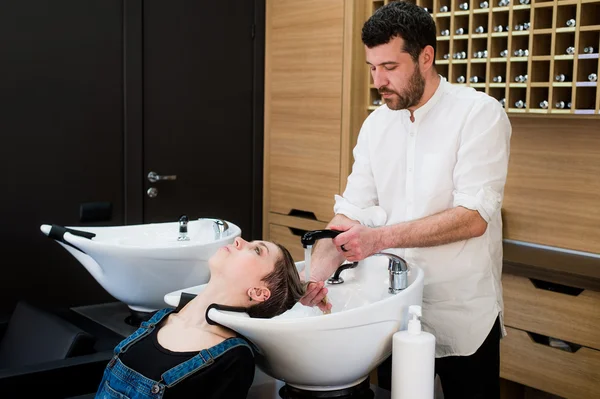 Peluquero lavando la cabeza a la mujer joven en la peluquería —  Fotos de Stock