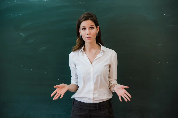 Mujer señalando con el dedo el tablero en blanco. Profesor de escuela señalando con el dedo a un tablero en blanco. Estudiante se para en la pizarra. Mujer de negocios presentando la idea a la junta. Chica en la escuela . —  Fotos de Stock