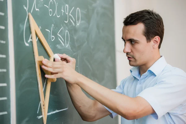 Genç öğretmen veya öğrenci formülü ile bir kara tahta üzerinde üçgen çizmek — Stok fotoğraf