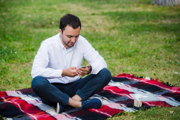 Joven hombre de negocios en el parque trabajando con la tableta — Foto de Stock